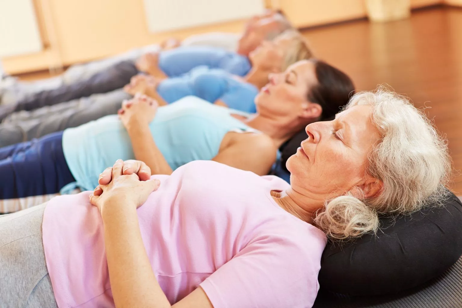 Progressive Muskelentspannung - fünft Personen entspannt liegend auf dem Boden
